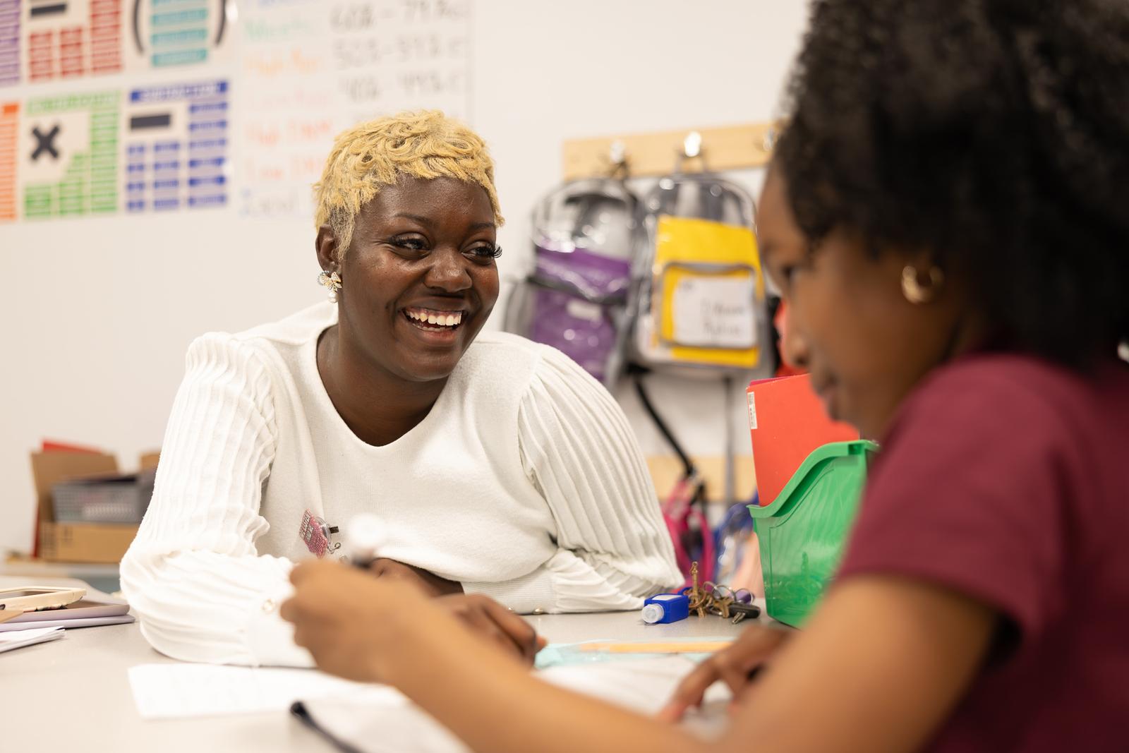 A teacher smiling during a one-on-one working conversation